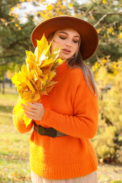 Junge modische Frau hält Blumenstrauß aus goldenen Blättern im Herbstpark - Foto, Bild