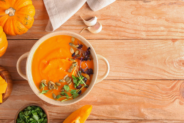 Горшок с вкусным супом из тыквенного крема на деревянном фоне - Фото, изображение
