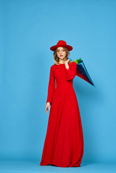 woman in red dress multicolored umbrella blue background - Foto, afbeelding