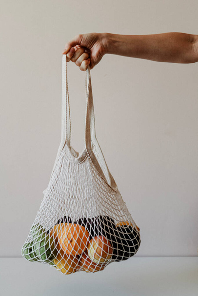 Το κορίτσι κρατάει μια οικολογική τσάντα γεμάτη φρούτα.. - Φωτογραφία, εικόνα
