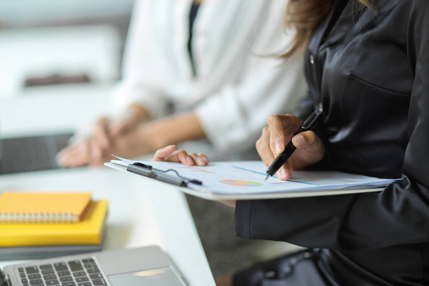 Image recadrée de femmes d'affaires examinant et gérant leur travail sur des documents de rapport dans un espace de travail de bureau - Photo, image