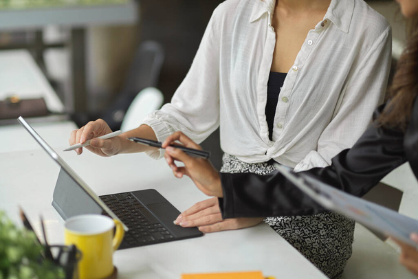 Deux femmes d'affaires qui travaillent ensemble avec une tablette numérique dans un bureau moderne à espace ouvert. - Photo, image
