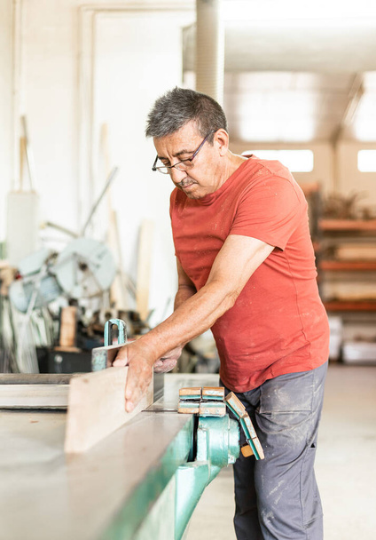 Hombre adulto enfocado a trabajar manualmente con una cepilladora de madera - Foto, imagen