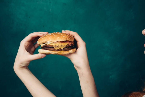 hamburger in hands close-up fast food green background - Foto, Imagen