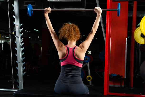 Woman bodybuilder engaged with a barbell in the gym - Фото, зображення