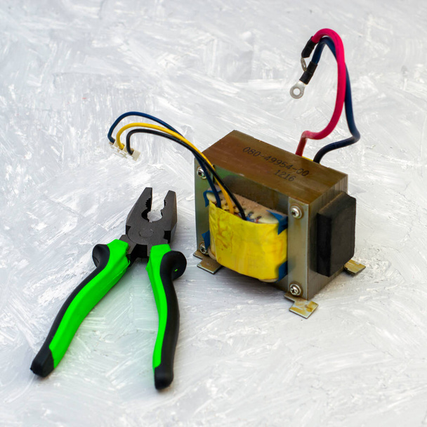 elektrický transformátor a kleště na šedém povrchu. Kvalitní fotografie - Fotografie, Obrázek