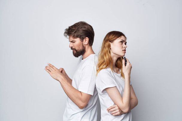 házaspár fehér pólóban, telefonnal a kezükben stúdió életmód - Fotó, kép