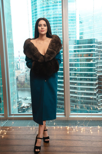 Gorgeous woman in coat standing in modern apartaments - Valokuva, kuva