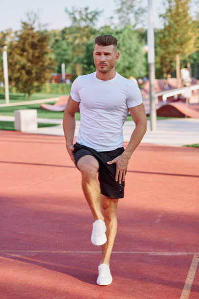 athletic men doing exercises on the sports ground in summer - Foto, afbeelding