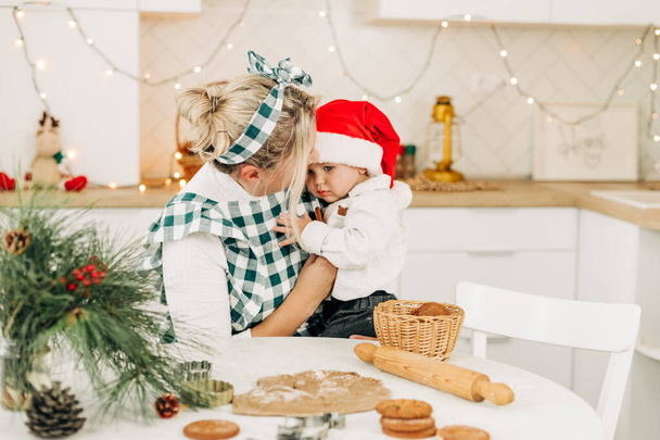 Mom and her little son bake Christmas cookies together. Christmas spirit, a family tradition - Foto, afbeelding