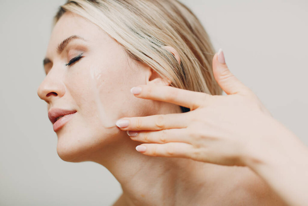 Aceite cosmético jalea real aplicación en la cara de la mujer adulta joven - Foto, imagen