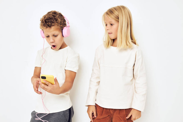 Image of boy and girl looking at the phone posing  on isolated background. High quality photo - Photo, Image