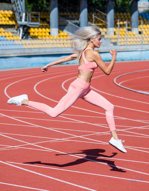Full of energy. female athlete ready for sprint sport workout. trainer or coach training. marathon. energetic and sporty. sexy fitness woman in sportswear. athletic lady run on stadium running track - Photo, Image