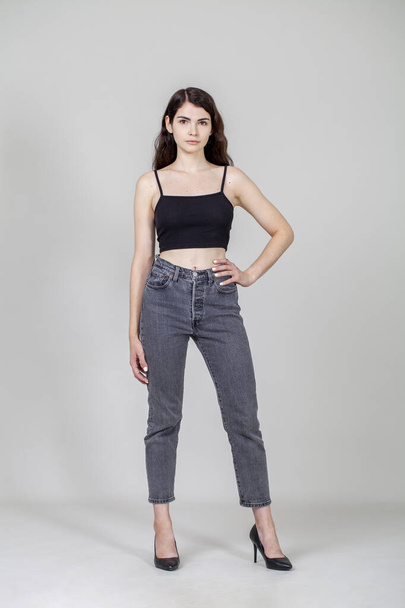 Full body portrait of a young beautiful brunette model in gray jeans - Фото, изображение