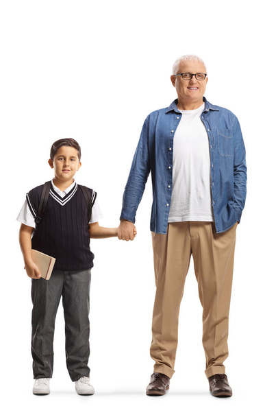 Full length portrait of a father and son in a school uniform holding hands isolated on white background - Photo, image