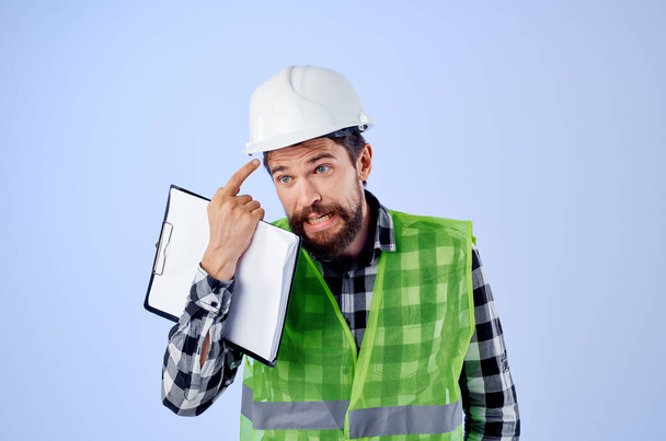 male builder in a green vest on  blue background. High quality photo - Φωτογραφία, εικόνα