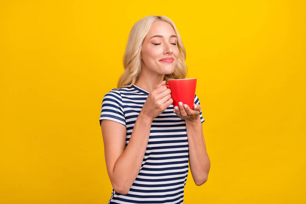 Portrait of attractive dreamy cheerful girl drinking smelling latte good morning isolated over shine yellow color background. - Фото, изображение