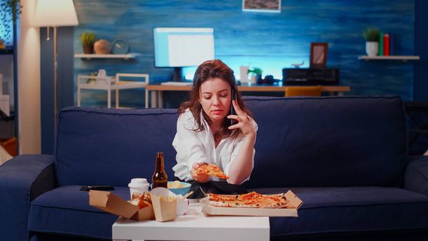 Annoyed woman talking on phone call while holding slice of pizza - Photo, Image
