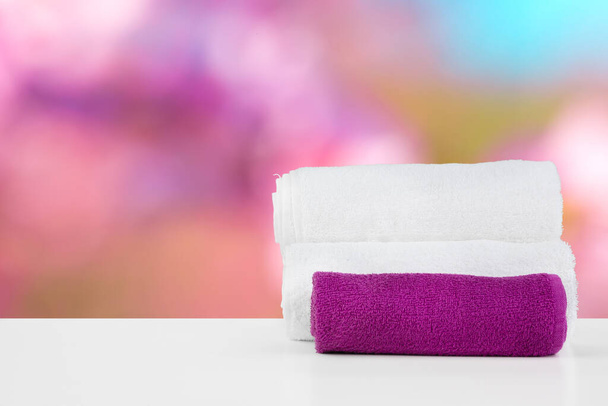 Stacked white spa towels on table against blurred background - Valokuva, kuva
