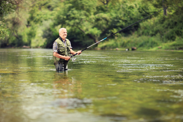 Mature fisherman fishing in river - Zdjęcie, obraz