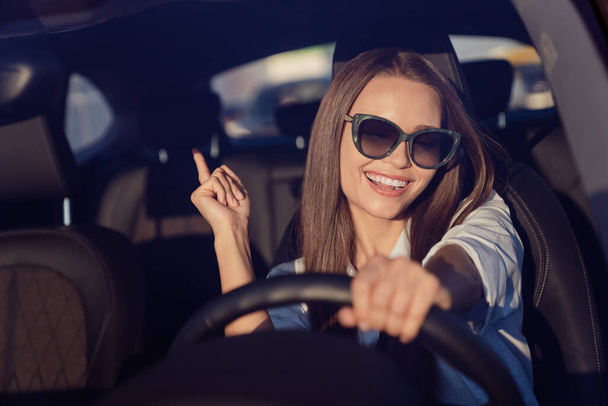 Foto portret glimlachende vrouw dragen zonneglas genieten van muziek rijden auto in de zomer. - Foto, afbeelding