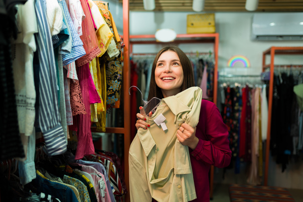 Femme attrayante excitée se sentant heureuse après avoir trouvé un chemisier haut de seconde main au magasin d'épargne - Photo, image