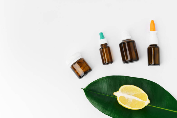 Essential oil in a small bottle with green leaf on white background - 写真・画像