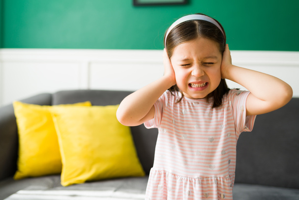 Ich will nicht auf meine Eltern hören. Aufgebrachtes kleines Mädchen verdeckt ihre Ohren wegen Schreien und lauten Geräuschen zu Hause  - Foto, Bild