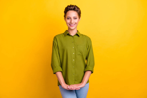 Photo of charming positive lady hold hands beaming smile wear green shirt isolated yellow color background. - Fotoğraf, Görsel