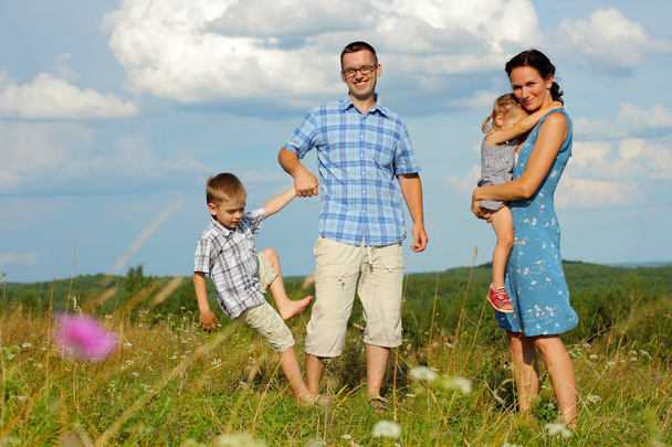 Familia de cuatro divirtiéndose en la cima de la colina
 - Foto, imagen