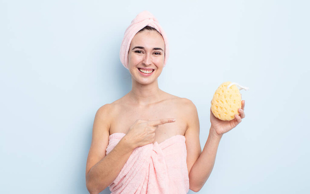 young pretty woman smiling cheerfully, feeling happy and pointing to the side. shower and sponge concept - Fotó, kép