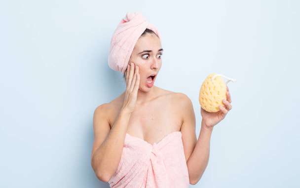 young pretty woman feeling happy, excited and surprised. shower and sponge concept - Foto, Imagem