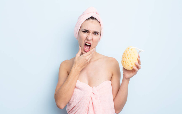 young pretty woman with mouth and eyes wide open and hand on chin. shower and sponge concept - Fotografie, Obrázek