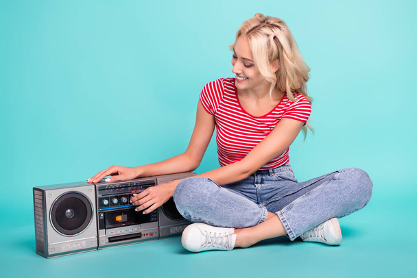 Full length photo of cheerful attractive woman sit floor boombox listen music isolated on teal color background. - Zdjęcie, obraz