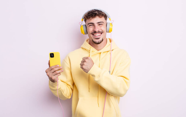 young handsome man feeling happy and facing a challenge or celebrating. music concept - Fotoğraf, Görsel