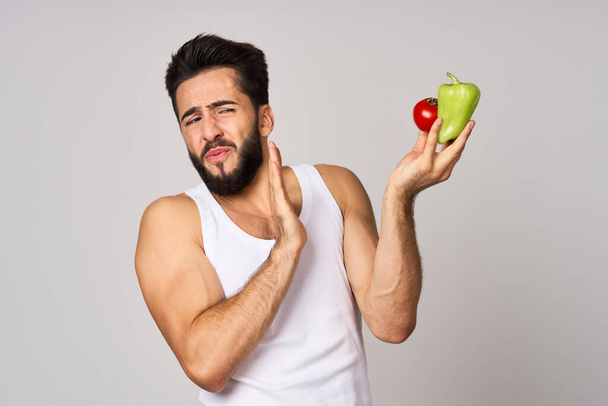 a man in a white t-shirt with vegetables in his hands healthy food diet - Foto, immagini