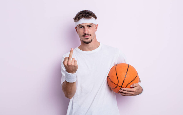 young handsome man feeling angry, annoyed, rebellious and aggressive. basketball concept - Фото, зображення