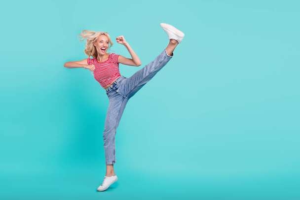 Photo of charming strong young lady wear striped t-shirt practicing karate looking empty space smiling isolated turquoise color background. - Foto, Bild