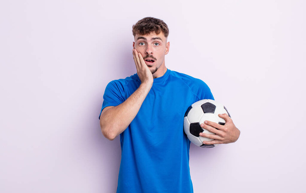 young handsome man feeling shocked and scared. soccer concept - 写真・画像
