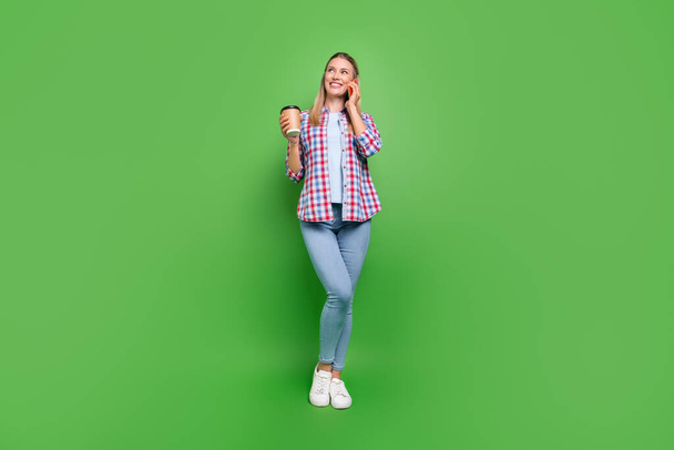 Full size foto van jonge vrouw gelukkig positieve glimlach call talk smartphone drinken koffie geïsoleerd over groene kleur achtergrond. - Foto, afbeelding
