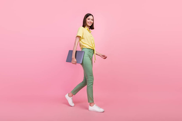 Full tělo profil boční fotografie mladé dívky šťastný pozitivní úsměv jít chůze setkání notebook izolované přes růžové barvy pozadí. - Fotografie, Obrázek