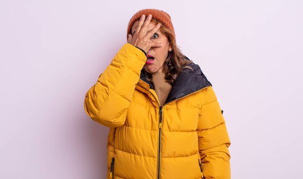 pretty middle age woman looking shocked, scared or terrified, covering face with hand. winter concept - Фото, зображення