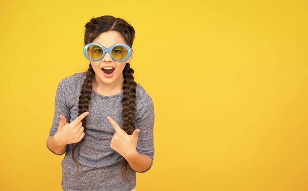 happy teen girl with braided hair wear sunglasses on yellow background, copy space, party fun - Valokuva, kuva