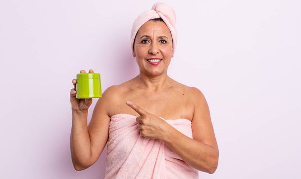 pretty middle age woman smiling cheerfully, feeling happy and pointing to the side. shower and hair product concept - Fotoğraf, Görsel