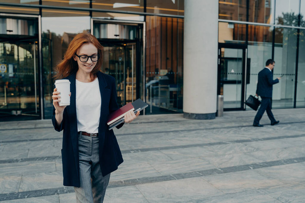 Outdoor shot van zakenvrouw draagt draagbare digitale tablet notebook voor het schrijven van notities koffie - Foto, afbeelding