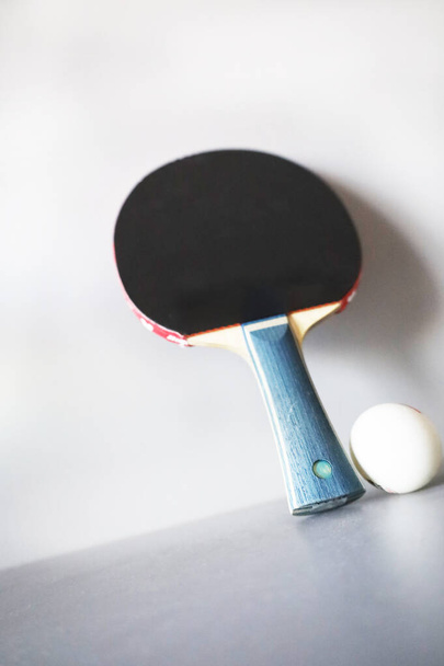 raqueta y pelota de ping pong sobre un fondo gris. - Foto, imagen