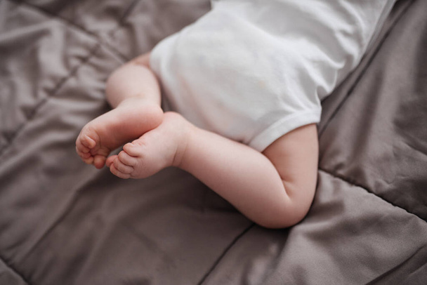Newborn feet. The child is lying on the bed. - Zdjęcie, obraz