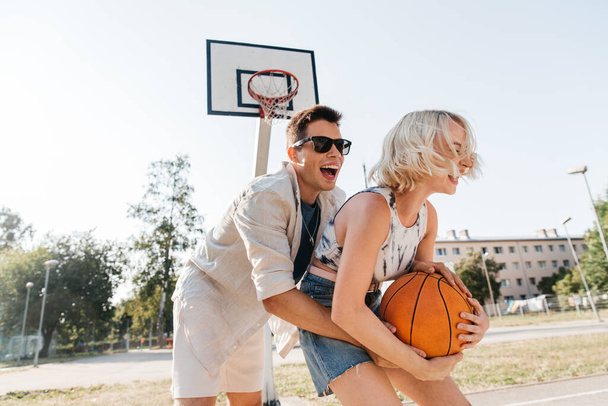 happy couple playing on basketball on playground - Foto, Imagen