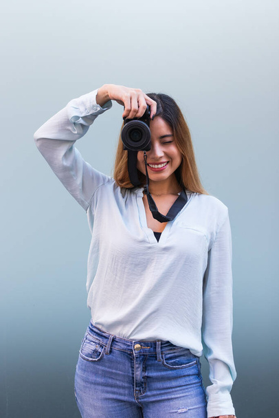 Portret fotografa uśmiechniętego podczas fotografowania profesjonalnym aparatem, piękna brunetka. Pojęcie hobby - Zdjęcie, obraz
