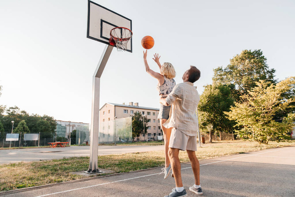 happy couple playing on basketball on playground - Zdjęcie, obraz